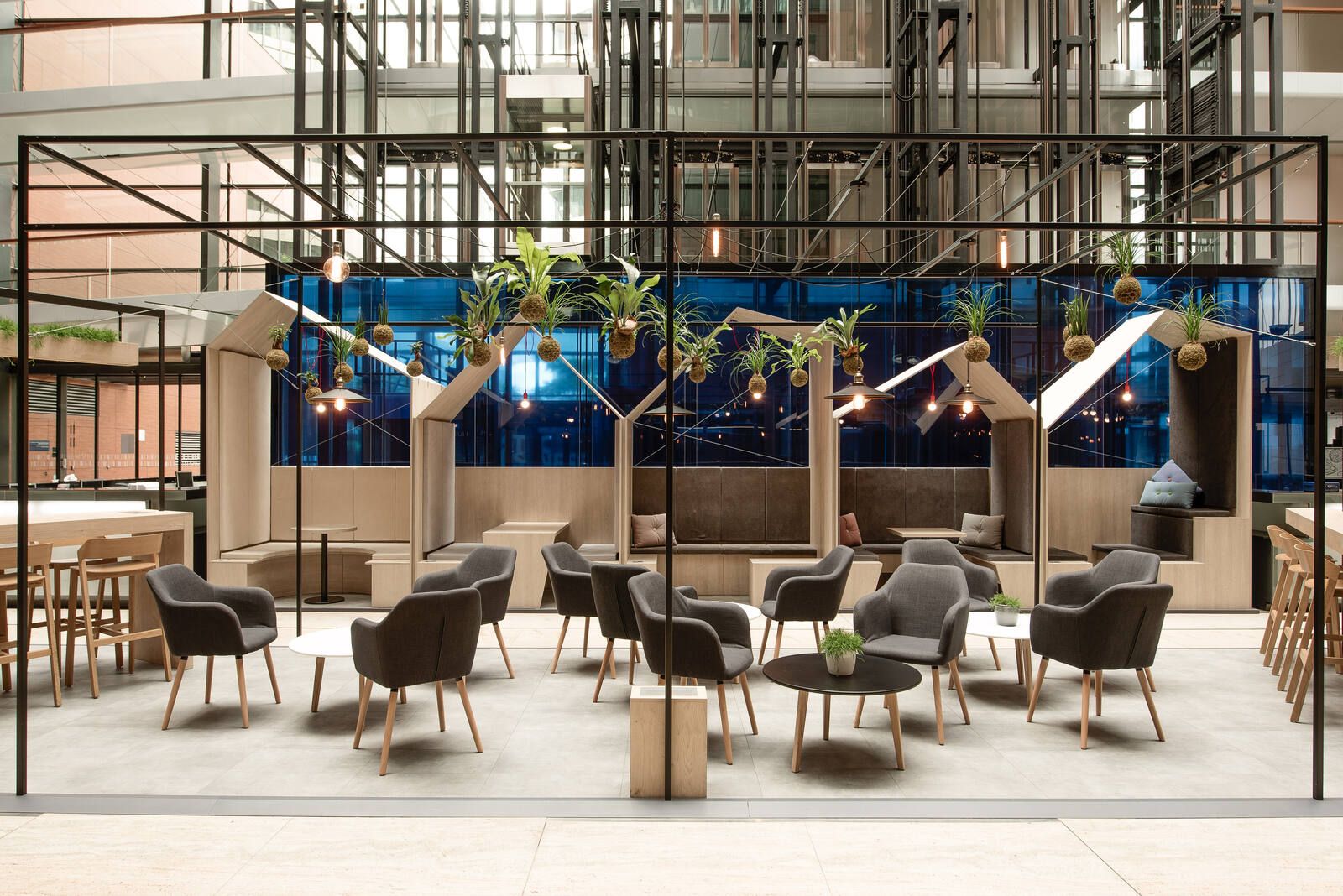 Hlavní pohled do atria — ocelový rastr se závěsnou kokedamou, meeting budky a lounge zóna